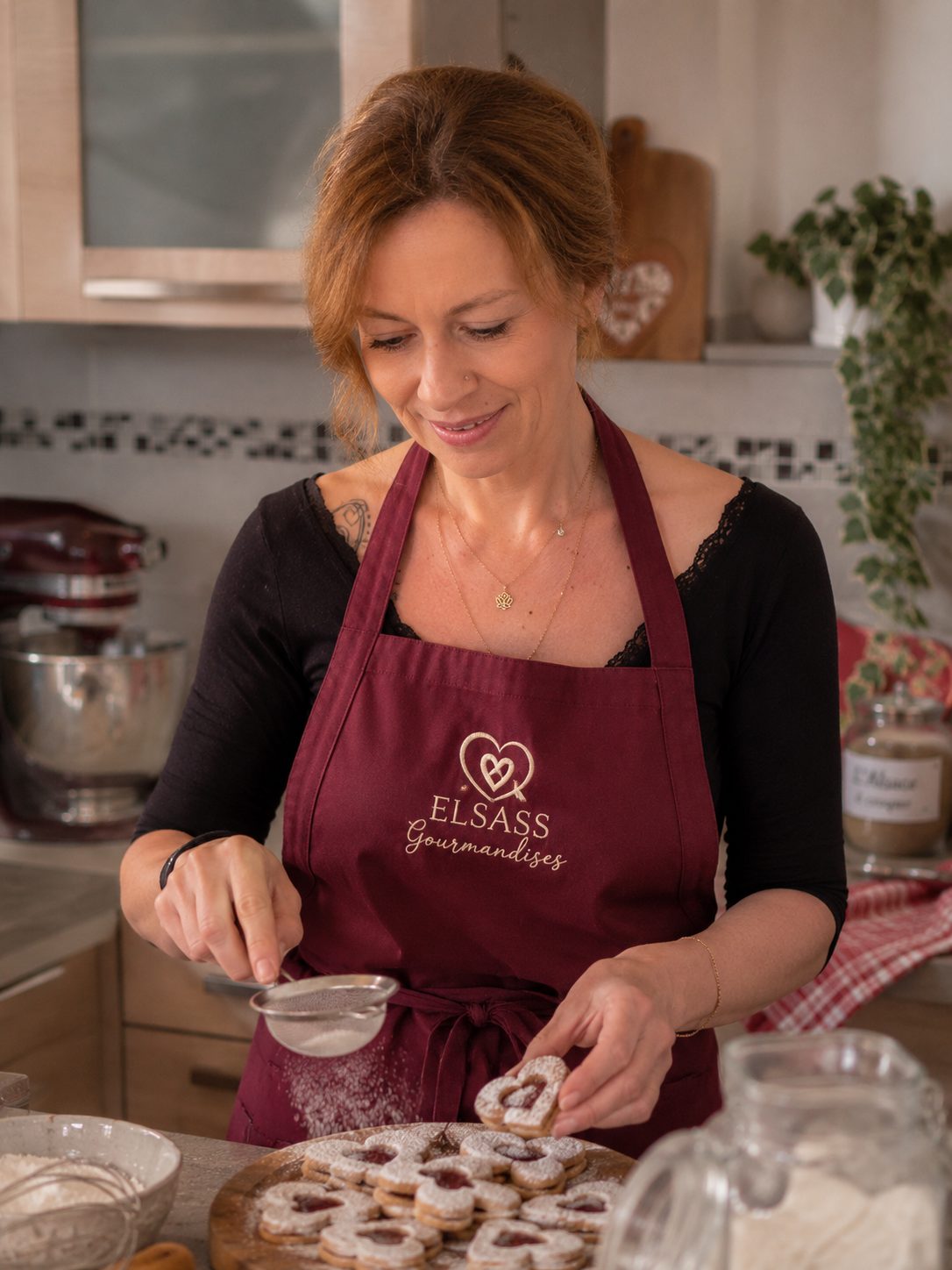 Vanessa, créatrice d'Elsass Gourmandises, saupoudrant du sucre glace sur des Bredela en forme de cœur